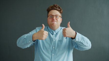 Man with glasses gives two thumbs up.