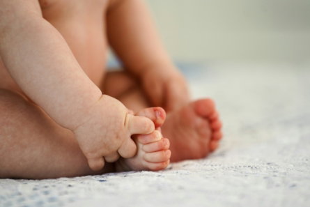 A close up of a baby laying on a bed