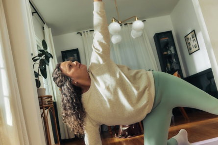 A woman does a yoga pose on a mat.