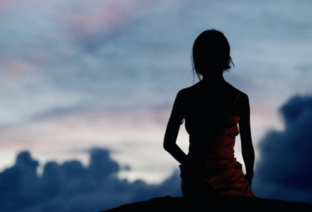 A silhouette of a woman standing on a hill